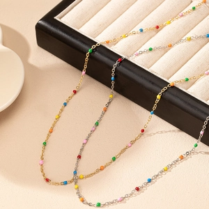 Macro shot of gold and silver chains with colorful enamel beads on a jewelry tray