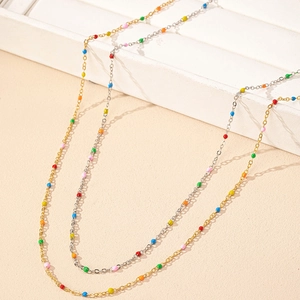 Delicate gold and silver beaded necklaces with colorful miniature round beads on light stand