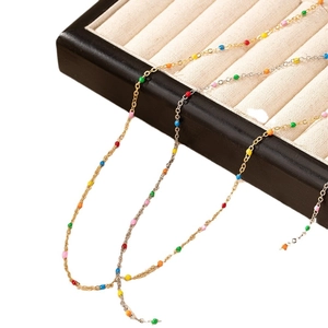 Chic gold and silver chains with colorful enamel beads displayed on a velvet jewelry tray