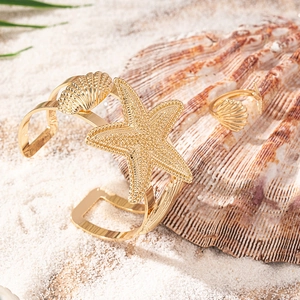 Set di gioielli dorati a tema oceano con stelle marine e conchiglie sulla sabbia