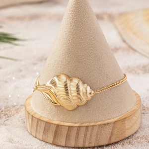 Detailed view of a golden conch shell pendant on a thin cross chain beach anklet