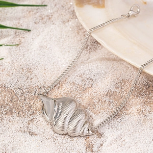 Chic conch shell anklet in silver finish lying on white beach sand for summer style