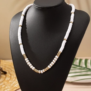 Collar bohemio con cuentas heishi blancas y detalles dorados en busto negro