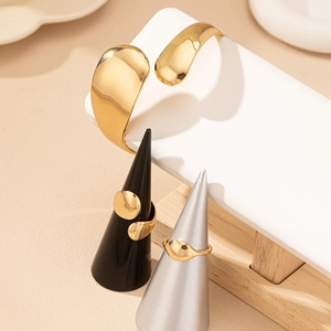 Bracciale rigido in oro lucido e anelli geometrici su espositori per gioielli professionali