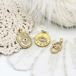 Makro-Detail von goldene Hamsa Hand und Böser Blick Anhängern mit Zirkonia-Steinen