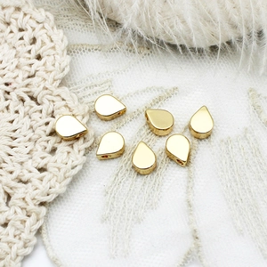 Detailed view of 18K gold plated teardrop beads for DIY jewelry making in soft lighting
