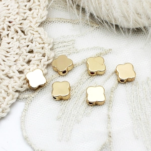 Macro detail of 18K gold-plated clover-shaped metal beads for DIY jewelry making