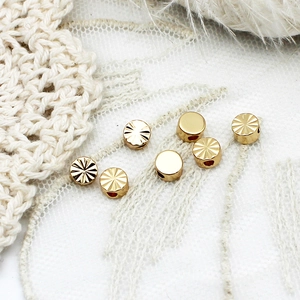 Detailed close-up of 18K gold plated cylinder spacer beads with sunburst pattern textures
