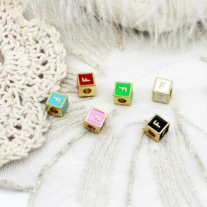 Détail de perles cubes émaillées lettre F en or 18K pour la création de bijoux