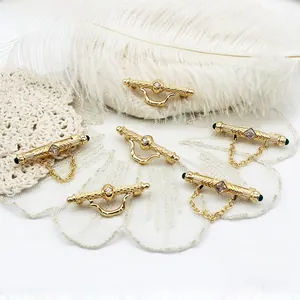 Detail of 18K gold-plated copper brooch clasp with white zircon and green bead accents