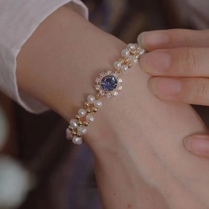 Close-up of a vintage pearl bracelet with purple sapphire pendant and micro-pave zircons
