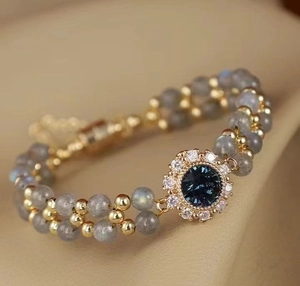 Macro detail of blue sapphire pendant and double-row gemstone bracelet in French retro style