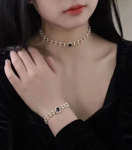 Detail of elegant pearl choker and bracelet set with blue gemstone on a fashion model