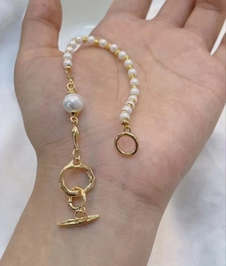 Détail d'un bracelet de perles blanches fait main avec un fermoir OT doré