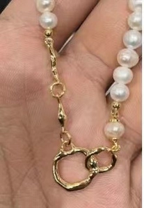 Vue macro du collier en perles baroques dorées avec pendentifs anneaux martelés