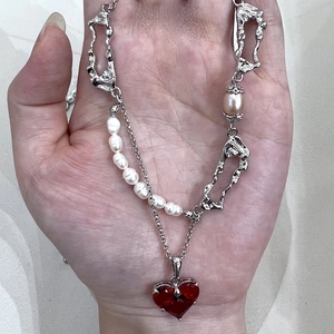 Lava style heart pendant necklace with pearls and red gemstone held in hand