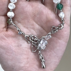 Detail of silver lava pendant with irregular pearls and emerald bead on hand