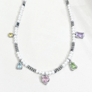 Detail view of pearl necklace featuring colorful zircon heart and teardrop pendants