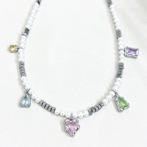 Macro detail of colorful crystal pendants and white pearls on a stylish charm necklace