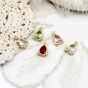 Macro shot of colorful pear-shaped zircon pendants with gold frames on lace background