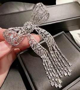Macro shot of a silver bow brooch with pavé zircon crystals and long cascading tassels