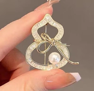 Detailed view of gourd-shaped gold brooch with micro-pave cubic zirconia and a white pearl