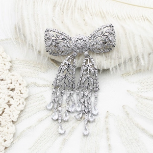 Luxurious silver bow brooch with dangling fringe tassels and leaf accents for formal gowns