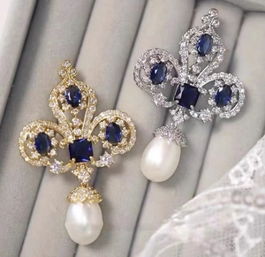 Detail of luxury vintage brooches with blue gemstones and hanging teardrop pearls