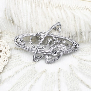 Elegant silver planet brooch with sparkling zircon inlays on a white feather background