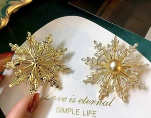 Detailed view showing the golden snowflake brooch front and the secure safety pin back