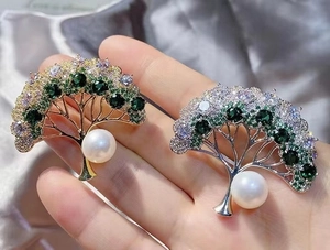 Detail of tree brooches with micro-set green gems and white pearls in silver and gold