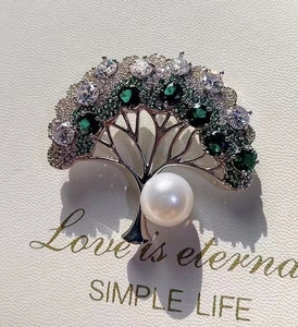 Detail of money tree brooch with emerald rhinestones and large white pearl on ivory card
