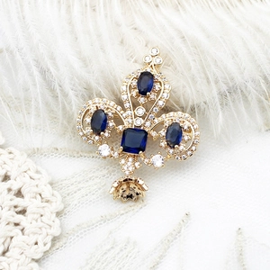 Luxurious gold tree crown brooch with deep blue gemstones on white lace fabric
