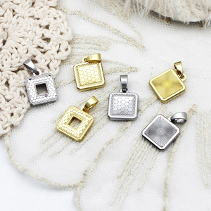 Macro shot of square geometric stainless steel charms with dot and ray texture details