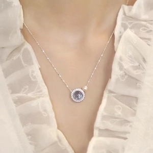 Collier argent avec pierre aigue-marine et perle porté sur une robe en dentelle