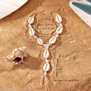 Minimalist shell and pearl barefoot sandal anklet with gold chain on beach sand
