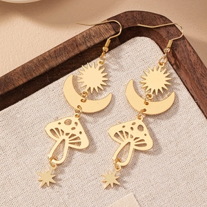 Détail de boucles d'oreilles dorées avec breloques soleil lune champignon et étoile