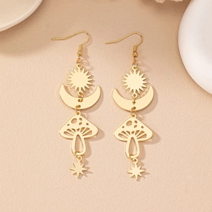 Détail de boucles d'oreilles bohèmes dorées avec soleil lune champignon et étoile