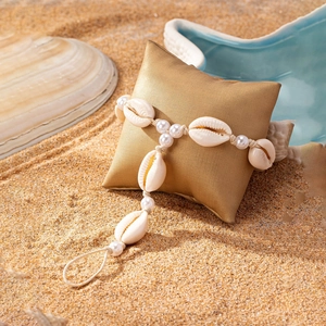 Handmade shell and pearl anklet with bohemian design on sand beach background