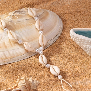 Bohemian seashell and pearl anklet jewelry on a tropical beach sand background
