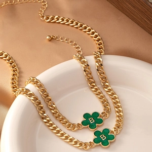 Detailed view of golden Cuban chain with green enamel four-leaf clover letter B pendants