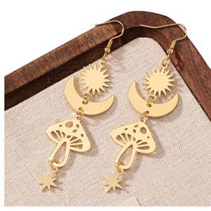 Boucles d'oreilles bohèmes dorées étoile lune et champignon sur plateau en bois vintage