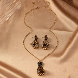 Detail of vintage gold bell jewelry set with flower motifs on golden silk background