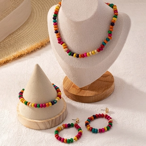 Detailansicht eines bunten Holzperlen-Schmucksets im Boho-Stil auf weißen Ständern