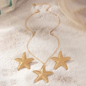 Goldenes Seestern-Schmuckset mit strukturierter Halskette und Ohrringen auf weißem Sand