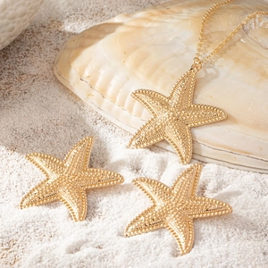 Goldenes Seestern-Schmuckset mit strukturierter Halskette und Ohrringen am Strand