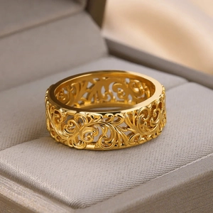 Detail of gold-plated ring with intricate hollow vine swirl textures in jewelry box