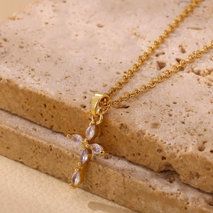 Detalle macro del collar con colgante de cruz bañada en oro de 18K con piedras de circón