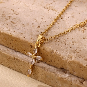 Detalle macro de un colgante de cruz chapado en oro de 18 quilates con circonitas marquise