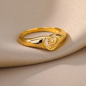 Polished gold-plated heart ring with intricate sunflower detail on silk background